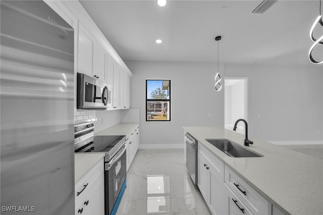 kitchen featuring tasteful backsplash, baseboards, appliances with stainless steel finishes, marble finish floor, and a sink