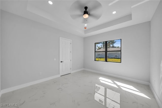 spare room featuring baseboards, a tray ceiling, recessed lighting, ceiling fan, and marble finish floor