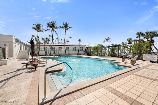 community pool with a patio area and fence