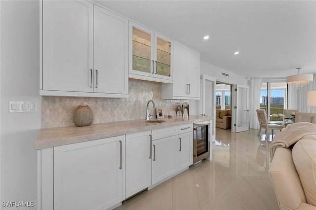 kitchen featuring open floor plan, beverage cooler, tasteful backsplash, and a sink