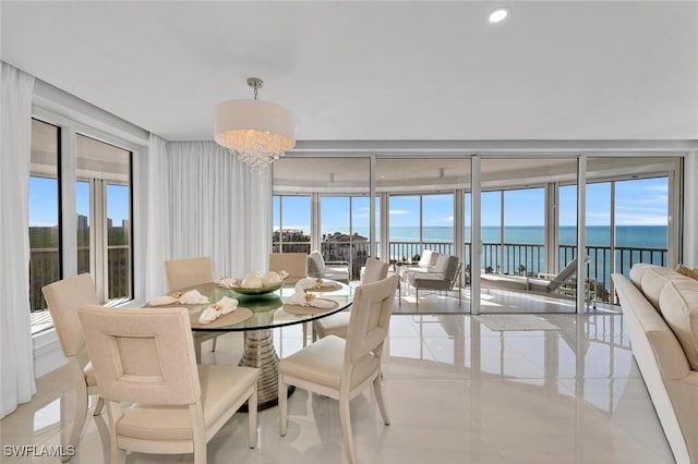 dining room with recessed lighting, a water view, plenty of natural light, and an inviting chandelier