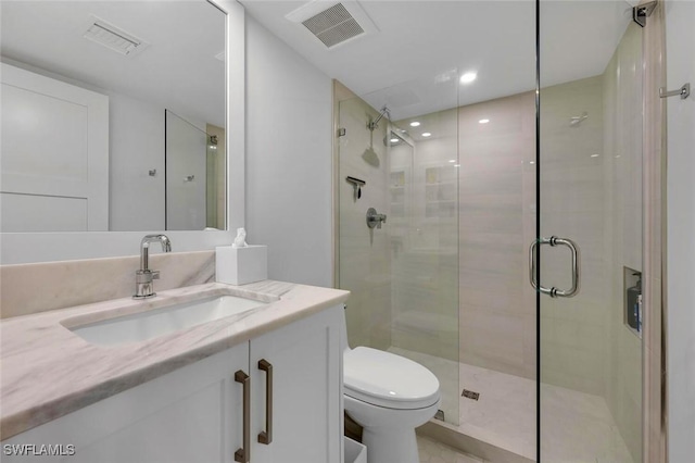 bathroom featuring toilet, a stall shower, vanity, and visible vents