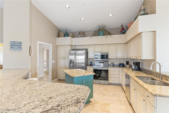 kitchen with stainless steel appliances, a kitchen island, a sink, and light stone countertops