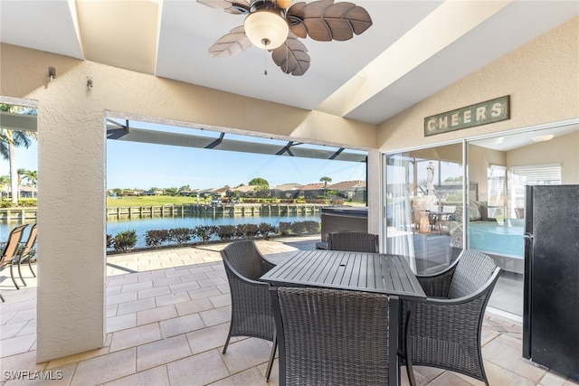 view of patio featuring a ceiling fan, outdoor dining area, a water view, and a lanai