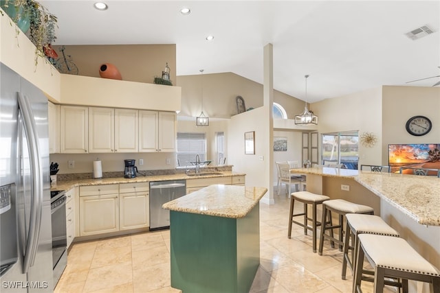 kitchen with stainless steel appliances, a kitchen island, a sink, visible vents, and light stone countertops