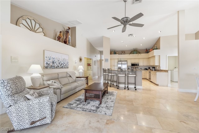 living area with baseboards, visible vents, high vaulted ceiling, and a ceiling fan