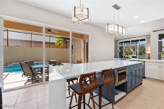 kitchen featuring light countertops, light tile patterned flooring, wall oven, and decorative light fixtures