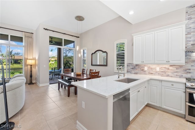 kitchen featuring light tile patterned flooring, a peninsula, a sink, appliances with stainless steel finishes, and decorative backsplash