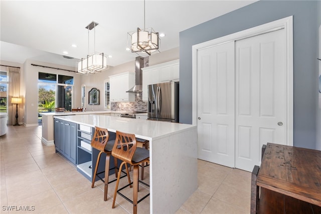 kitchen featuring light tile patterned floors, stainless steel appliances, wall chimney range hood, and decorative backsplash