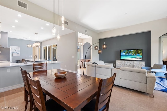 dining space with light tile patterned floors, arched walkways, visible vents, and recessed lighting