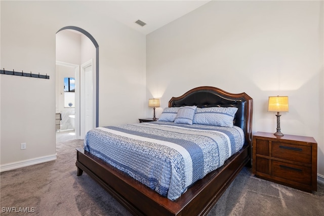 bedroom with carpet, arched walkways, visible vents, ensuite bathroom, and baseboards