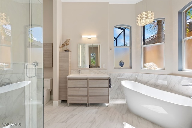 full bathroom featuring marble finish floor, toilet, a stall shower, vanity, and a freestanding tub