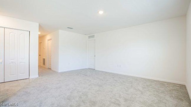 unfurnished bedroom featuring light carpet, baseboards, visible vents, and a closet