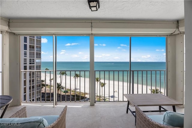 sunroom / solarium with a water view and a view of the beach