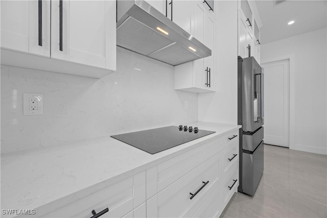 611 NW 25th Ter, Cape Coral, FL 33993 - kitchen with ventilation hood, black electric cooktop, stainless steel fridge, white cabinets, and light stone countertops