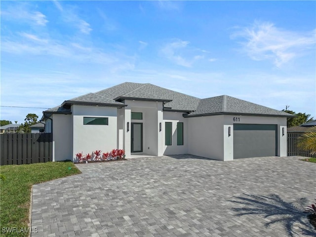 611 NW 25th Ter, Cape Coral, FL 33993 - prairie-style house featuring stucco siding, a garage, a shingled roof, and driveway