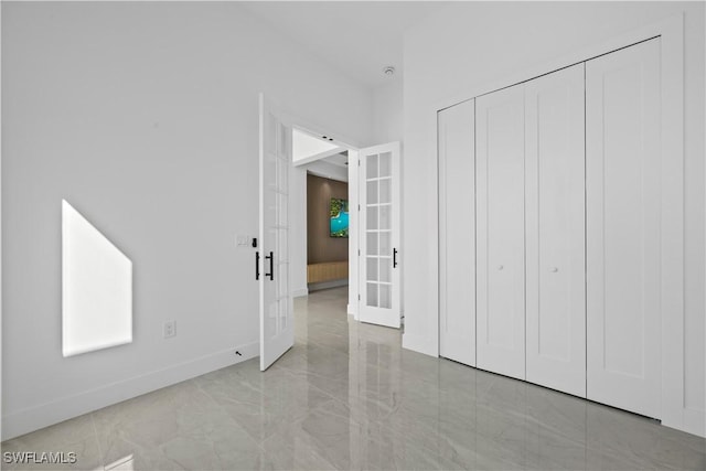 611 NW 25th Ter, Cape Coral, FL 33993 - unfurnished bedroom with french doors, a closet, and light marble finish floors