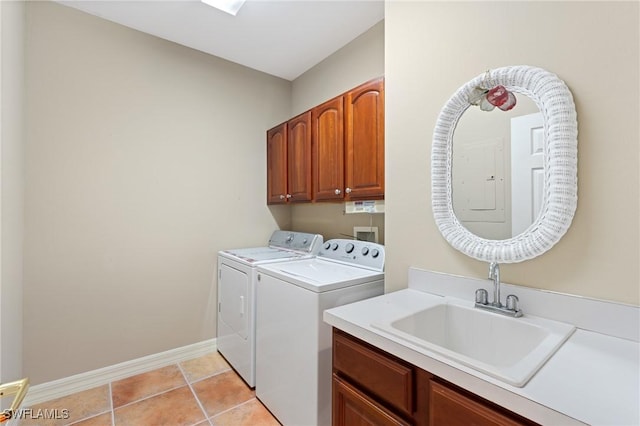 laundry area with cabinet space, light tile patterned floors, baseboards, washing machine and clothes dryer, and a sink