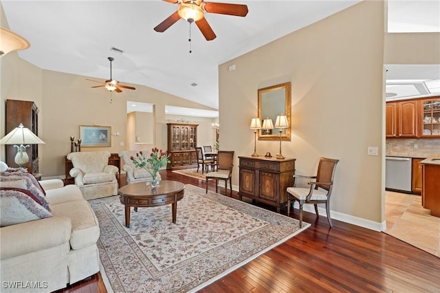 living room with a ceiling fan, visible vents, vaulted ceiling, baseboards, and hardwood / wood-style floors