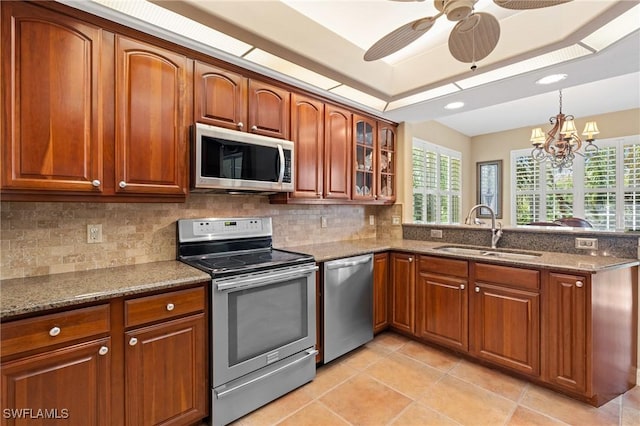 kitchen with stainless steel appliances, stone countertops, a sink, and a peninsula