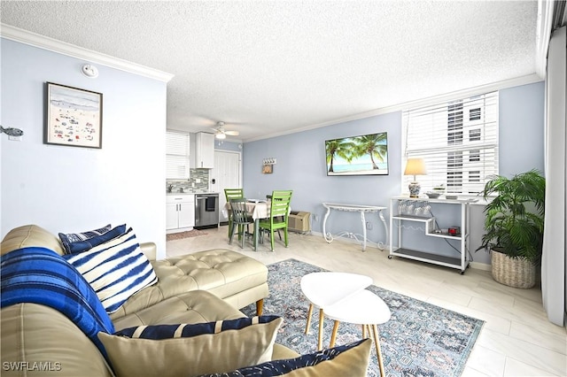 living room featuring a ceiling fan, baseboards, ornamental molding, and a textured ceiling