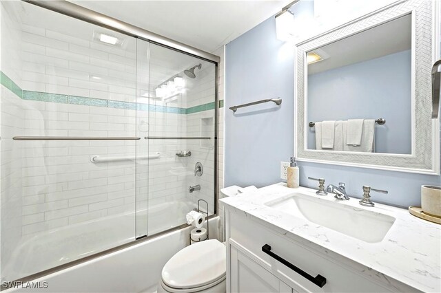 full bath featuring bath / shower combo with glass door, vanity, and toilet