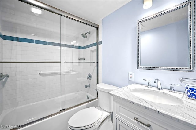 bathroom featuring toilet, bath / shower combo with glass door, and vanity