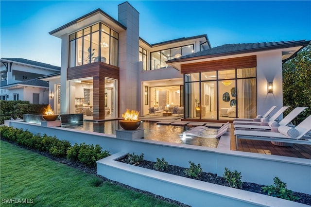 rear view of house featuring outdoor lounge area, a patio, a chimney, and a balcony