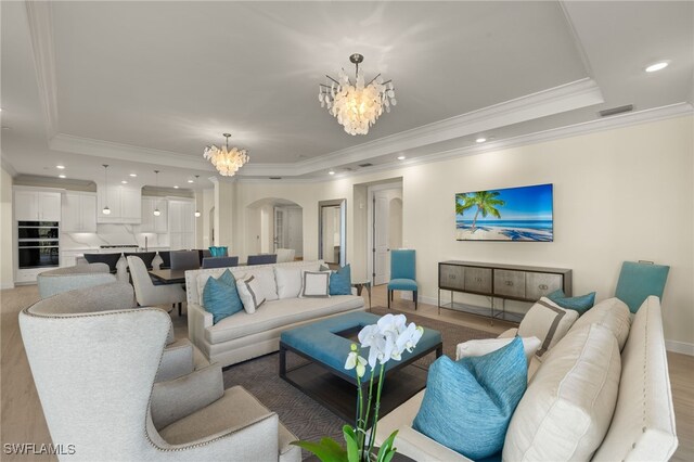 living area with a tray ceiling, arched walkways, recessed lighting, an inviting chandelier, and baseboards