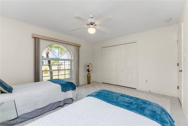 bedroom featuring a ceiling fan, a closet, baseboards, and light tile patterned floors