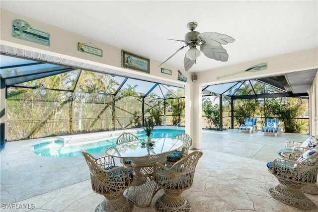 exterior space featuring outdoor dining space, glass enclosure, a patio, and ceiling fan