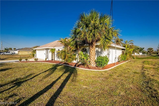 view of front of property featuring a garage, driveway, a front lawn, and stucco siding