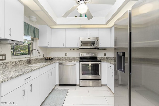 kitchen with stainless steel appliances, a raised ceiling, white cabinets, and a sink