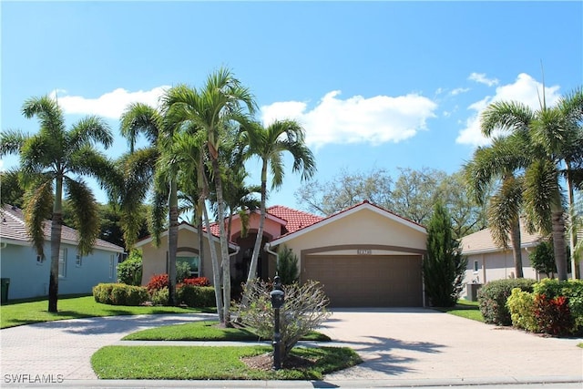 view of front of house with a garage, cooling unit, decorative driveway, a front lawn, and stucco siding