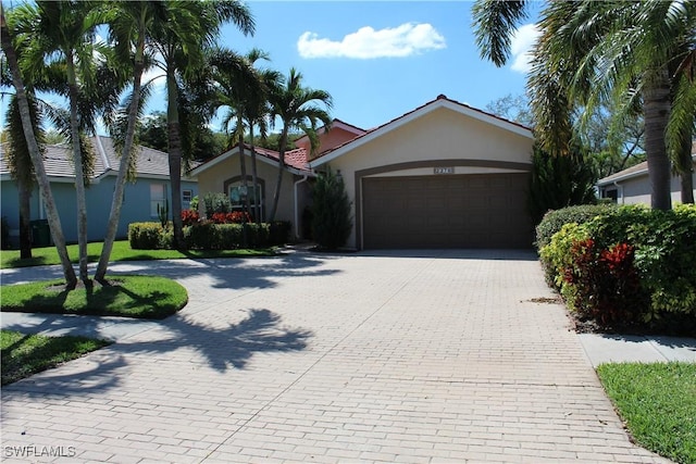 ranch-style house featuring a garage, decorative driveway, and stucco siding