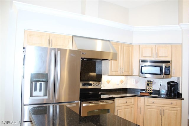 kitchen featuring light brown cabinets, stainless steel appliances, wall chimney exhaust hood, tasteful backsplash, and dark stone countertops