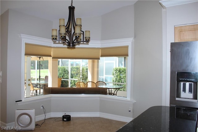 dining room with a healthy amount of sunlight, tile patterned flooring, a chandelier, and baseboards