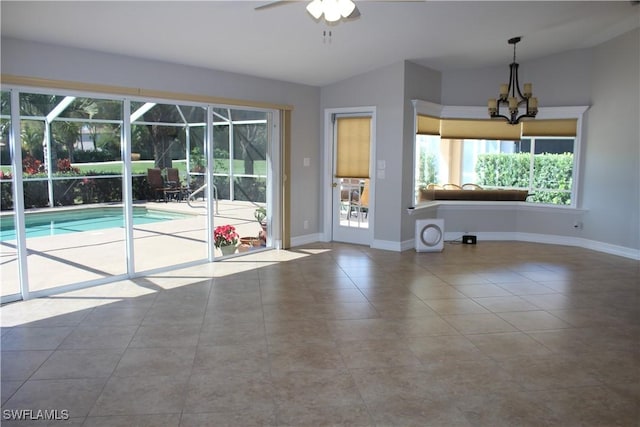 interior space featuring a sunroom, vaulted ceiling, baseboards, and ceiling fan with notable chandelier