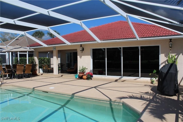 rear view of house with a patio area, a tile roof, an outdoor pool, and stucco siding