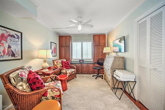 sitting room featuring ornamental molding, light colored carpet, and a ceiling fan