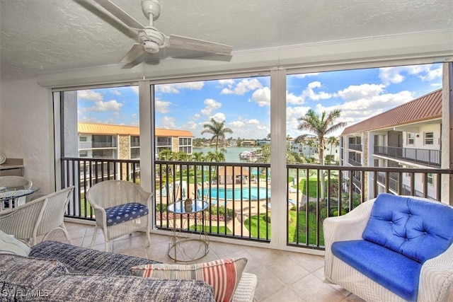 sunroom / solarium featuring a water view and a ceiling fan