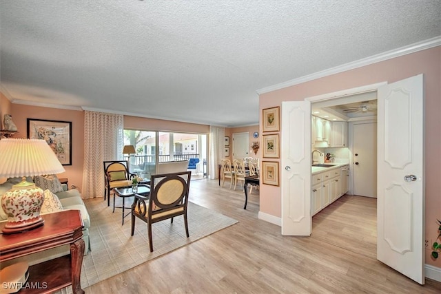 dining room featuring ornamental molding, baseboards, light wood-style flooring, and a textured ceiling