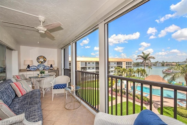 sunroom featuring a water view and a ceiling fan