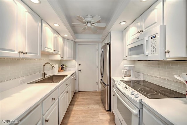 kitchen featuring white appliances, white cabinetry, light countertops, and a sink