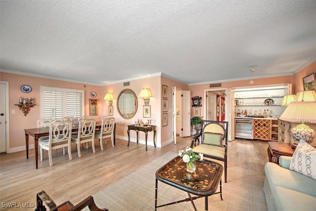 living area featuring crown molding, a dry bar, visible vents, light wood-style flooring, and beverage cooler