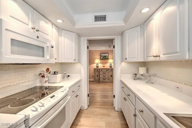 kitchen featuring white microwave, visible vents, white cabinetry, electric stove, and a raised ceiling