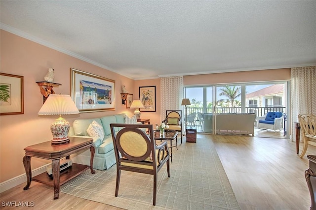 living area with ornamental molding, a textured ceiling, baseboards, and wood finished floors