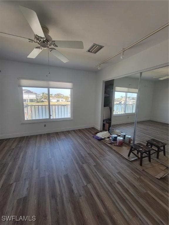 spare room featuring a healthy amount of sunlight, visible vents, baseboards, and wood finished floors