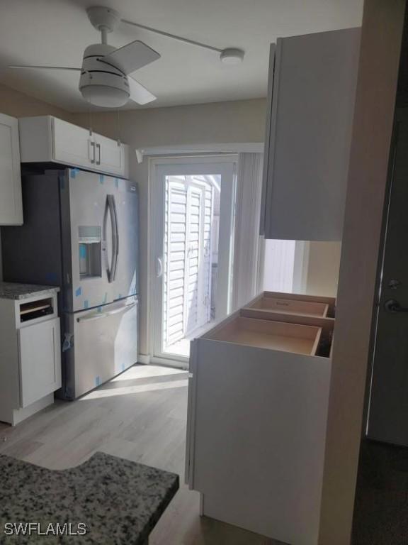 kitchen featuring a ceiling fan, light countertops, light wood-style floors, white cabinetry, and stainless steel refrigerator with ice dispenser