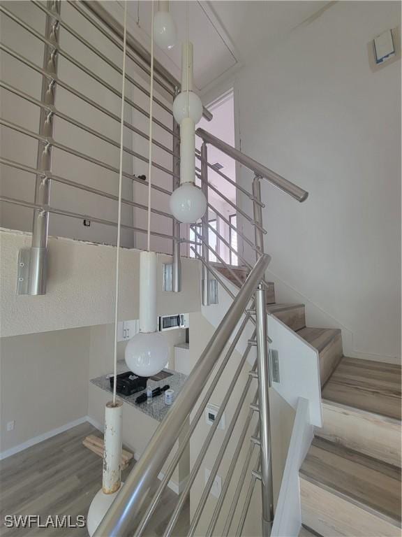 staircase with a high ceiling, baseboards, and wood finished floors